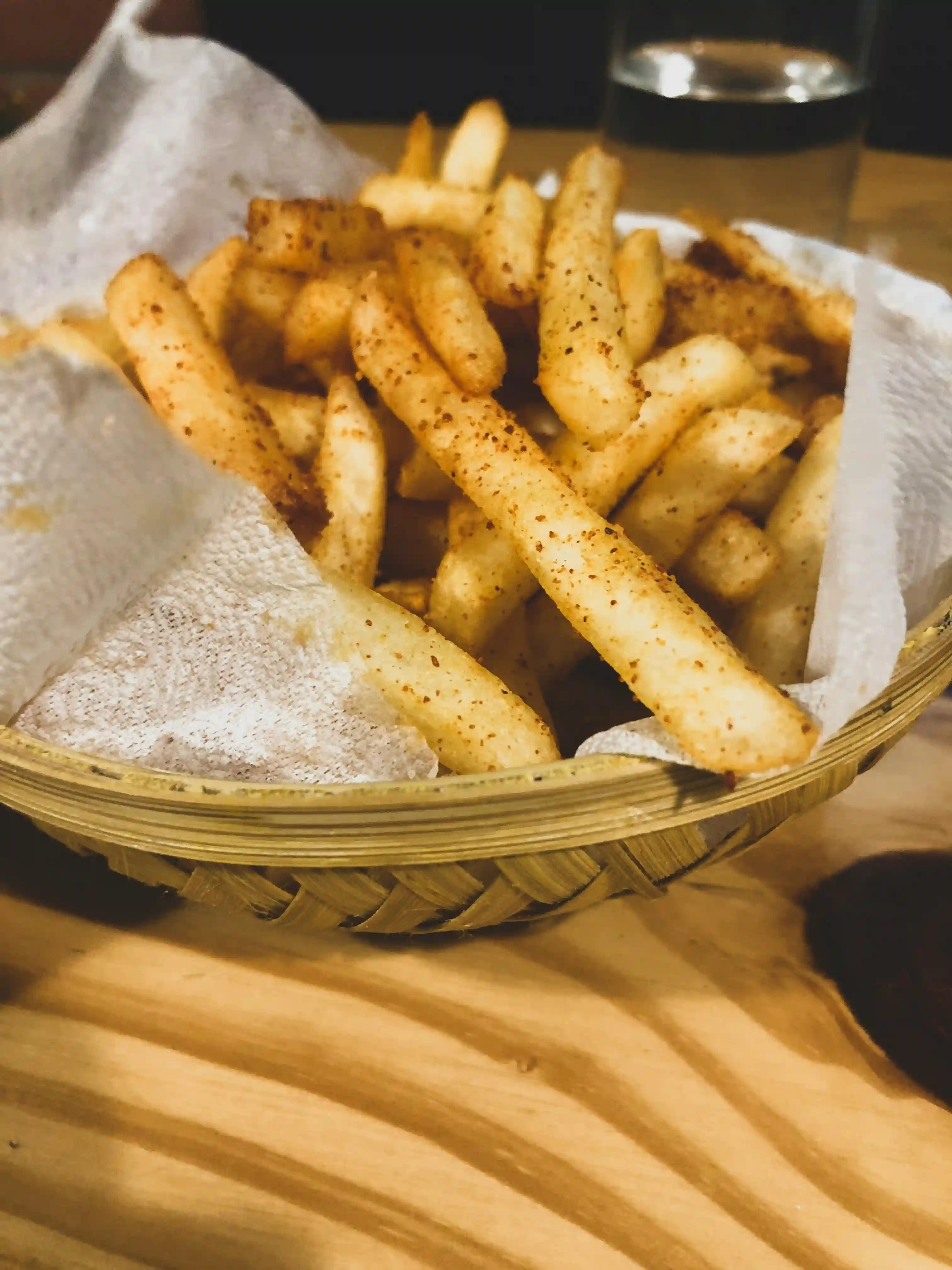 picture of seasoned classic cut fries on a weaved wooden bowl